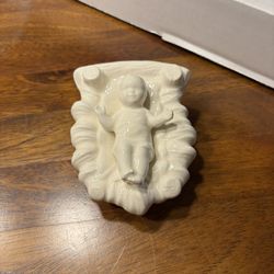 white porcelain figurine of the Baby Jesus in a manger