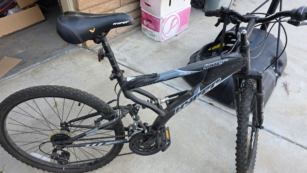 This is a used Hyper Havoc FS 26 mountain bike with a full-suspension aluminum frame and 26-inch wheels. It features 21 speeds with Shimano shifters a