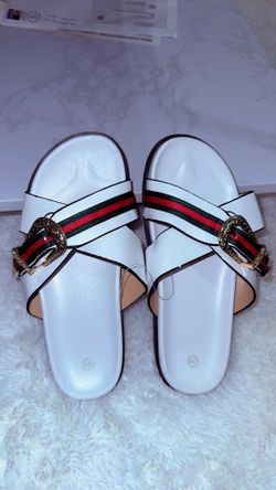 White leather slides with red and green striped webbing and gold buckle