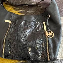 Black Michael Kors bag with a glossy front and two front zippers.