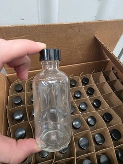 Box of 40 small round glass bottles with black screw cap lid