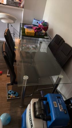 Glass and silver table with black chairs