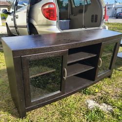 dark brown wooden media console or TV stand featuring glass-front cabinets and central open shelving.