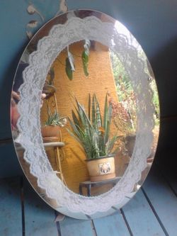 Oval mirror with lace stenciled design around the edge