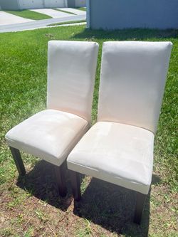 Pair of light-colored suede dining chairs.