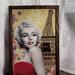 Marilyn Monroe, the iconic American actress and model of the 1950s. The image combines a portrait of the actress with Parisian-themed elements, includ