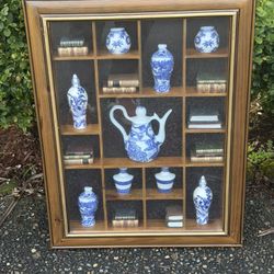 vintage oriental-style shadow box wall hanging featuring a collection of miniature blue and white porcelain items, such as vases and a teapot,books