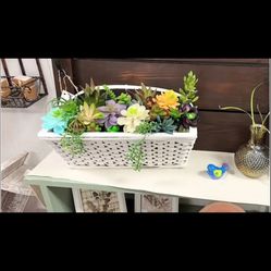 Decorative white wicker basket filled with colorful artificial succulents.