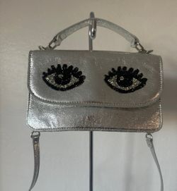 Betsy Johnson Silver Black Eye Top Handle Crossbody Purse.. pre owned very good condition.. This bag is so cute and very fashionable! This purse has c