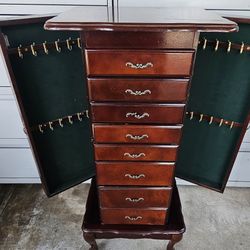 vintage Powell Jewelry Armoire featuring a cherry wood finish, eight drawers, and side panels for hanging necklaces. 