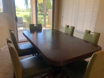 dark stain heavywood dining table with six green geomatric pattern chairs with handlebar