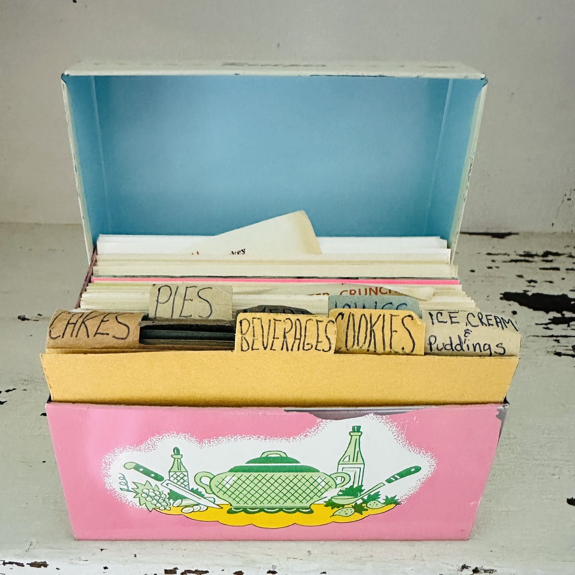 Vintage metal pink kitchen design recipe box filled with old recipe cards. Some of the recipes are handwritten some are cut out from magazines etc.