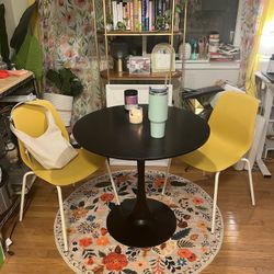 Black Bistro Table & Yellow Chairs & Floral Rug