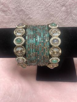 Pista green bangle set features intricate gold detailing, stone studding, and pearl accents