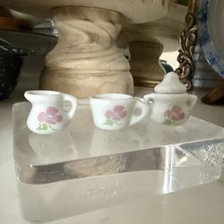 Itty-bitty set of Tiny Trinkets   Adorable little mini tea set. Has a creamer, a teacup, and a lidded sugar bowl. White with cute pink flower designs 