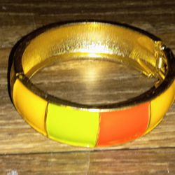 Add a playful touch to your outfit with this Rubik's Cube patterned bangle bracelet. Featuring vibrant colored squares in yellow, green, orange, and r