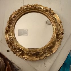 This is a vintage Florentine round mirror with a gold-gilded frame, handmade in Italy.