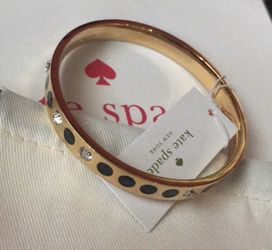 Kate spade bracelets in gold with pouch Kate Spade New York shiny 12-karat gold plated metal bracelet with glass stones and enamel fill Slide on ban