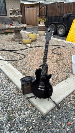 Black guitar set with amplifier, cable, tuner, and strap.