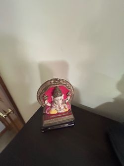 decorative tabletop idol or murti of Lord Ganesha set inside an ornate, red-backed arch frame.