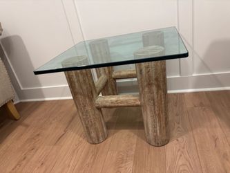 Rustic end table has a base constructed from heavy thick wooden logstabletop is thick tempered glass