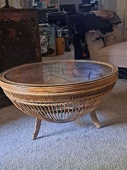 This is a vintage mid-century modern drum-form rattan and wicker coffee table featuring a glass top and distinct flared legs.