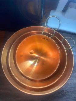 Copral set of three vintage nesting copper mixing bowls featuring attached brass ring handles.
