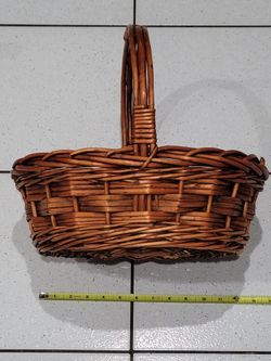 Vintage rustic woven wicker gathering basket featuring a sturdy vertical loop handle and a brown-stained finish.