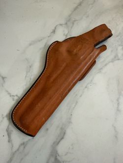 tan leather Bianchi 5BHL thumb-snap holster, featuring stamped maker's markings and a star emblem near the top break.