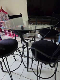 Round high glass table with 4 chairs.The table measures 36 inches in circumference.
