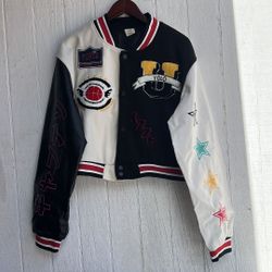 una chaqueta universitaria recortada de estilo Y2K con parches bordados y bloques de color, comúnmente comercializada por marcas como JJdocvanatic. C