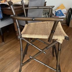 Pair of faux bamboo metal director’s bar stools with woven wicker seats — coastal boho style.