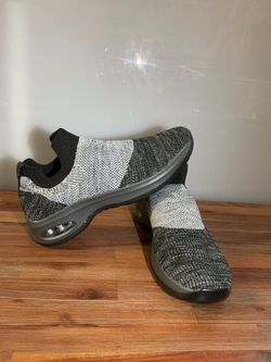 These Hypersoft sneakers feature a slip-on design with a gray and black mesh upper.  Estos tenis Hypersoft tienen un diseño sin cordones con una parte