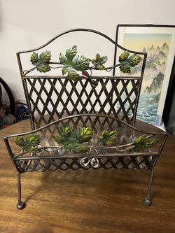 This is a vintage Italian tole bronze metal finish magazine rack featuring decorative green and yellow painted grape leaves with 4 attached glass grap