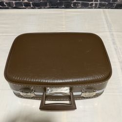  This vintage brown faux leather suitcase from the 1970s features classic chrome latches and a retro travel style. The true vintage piece exudes a tim