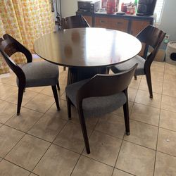 Holt Espresso 5 Piece Round Dining Set, featuring a rich espresso finish, a cylindrical slatted base, and four chairs with grey upholstered seats.