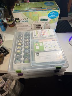 Cricut Create Personal Electronic Cutter With 37 Cricut Cartridges Stored In An Organizing Case With a Booklet.