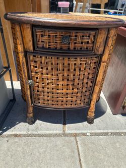 vintage burnt bamboo and rattan side table features a woven cabinet door and a top drawer.