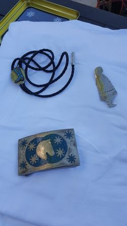 Silver cowboy belt buckle, bolo, and silver brooch.