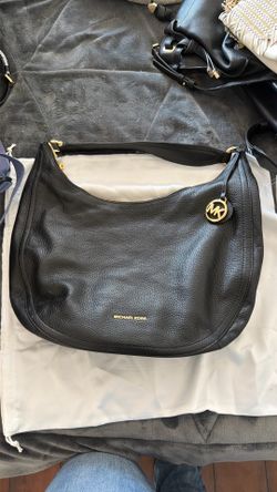This is a black pebbled leather Michael Kors Lydia shoulder bag featuring gold-tone hardware and a circular MK charm.