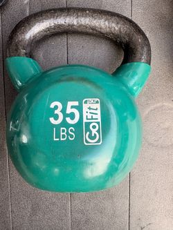 Durable 35 lb kettlebell is made of cast iron with a green vinyl coating. It has a textured handle for a secure grip.