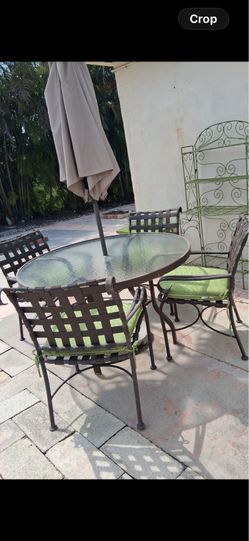 Six piece patio set with green cushions and an umbrella