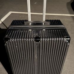 Black rolling lightweight plastic suitcase on four wheels with telescopic handle.