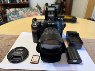 Professional Nikon D7100 digital SLR camera has a black body and is paired with an AF-S Nikkor 18-70mm 1:3.5-4.5G ED DX lens. This set includes a 32GB