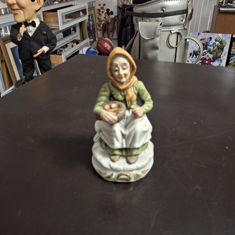 Vintage Porcelain Figurine Of A Lady With A Vegetable Basket Wearing A Green Dress Sitting On A Bench, Hand-painted 6.5" Tall
