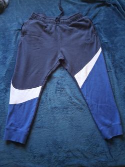 Comfortable Nike joggers with a navy, white, and blue colorblock design. These pants have an elastic waistband with a drawstring and side pockets. The