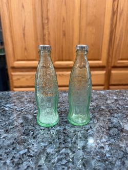 Vintage Light Green Glass Small Soda Bottles Pair of Salt and Pepper Shakers.  On the shakers it has “Coca Cola” written on them.  Size approximately 