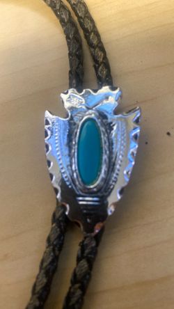 silver-tone arrowhead bolo tie featuring a turquoise stone