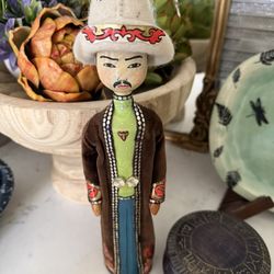 Unique Wooden Uzbekistan Folk Art doll. This figurine is a man in traditional clothing. Has white hat with red and gold designs. Wearing green shirt, 