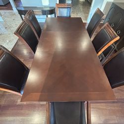 Large wooden dining table With 8 matching leather chairs. Good condition.